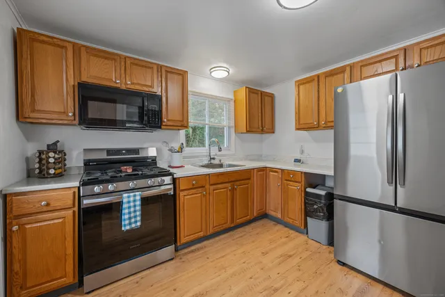 a kitchen with stainless steel appliances granite countertop a stove top oven a sink and a refrigerator