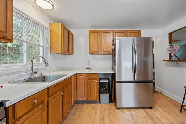 a kitchen with stainless steel appliances granite countertop a refrigerator sink and wooden cabinets