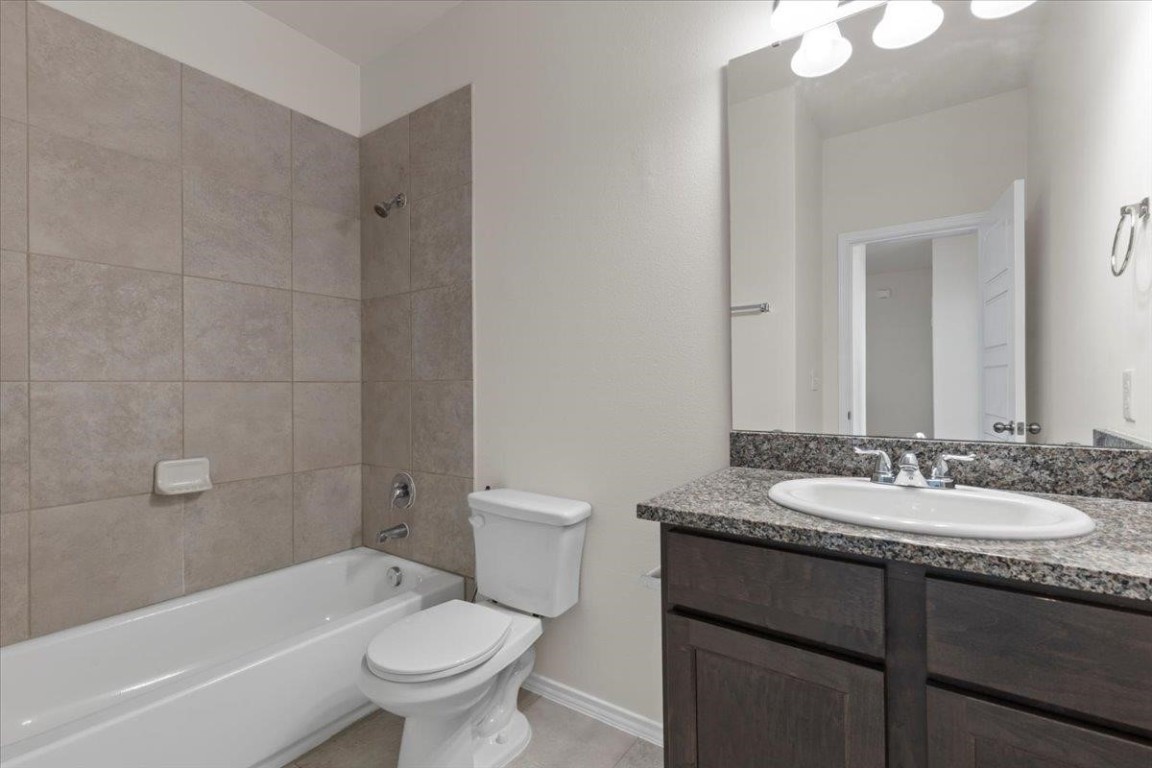128 Dodge Road Georgetown, TX 78626 - Photo 16 of 18 a bathroom with a granite countertop sink a toilet a mirror a bathtub and shower