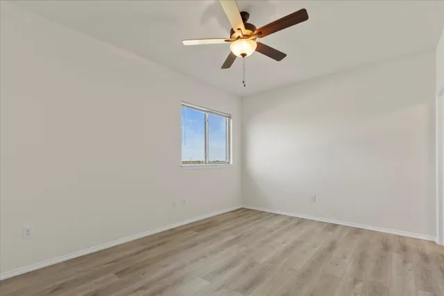 an empty room with a window and a fan
