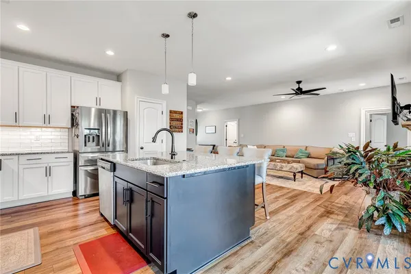 a kitchen with stainless steel appliances granite countertop a sink a stove and a wooden floors
