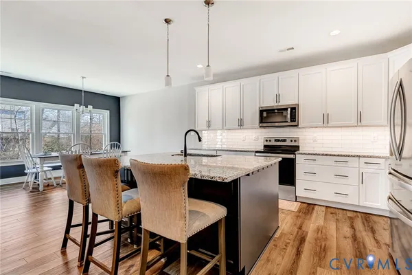 a kitchen with stainless steel appliances granite countertop a table chairs microwave and sink