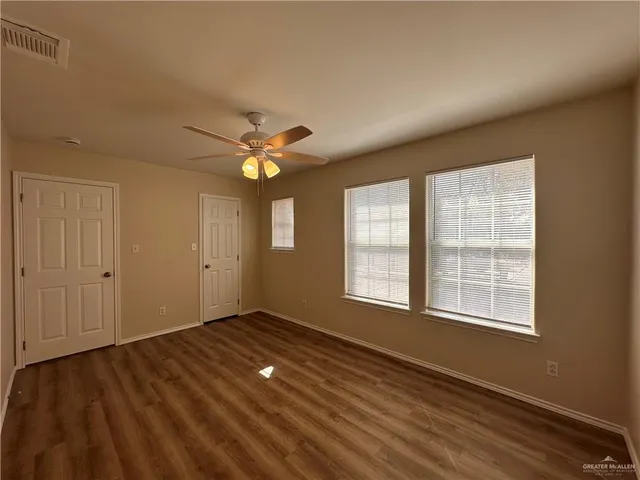 a view of an empty room with a window and wooden floor
