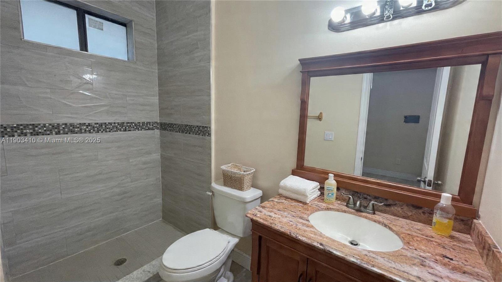 3301 Southwest 139th Avenue, Unit 3301 Miramar, FL 33027 - Photo 32 of 44 a bathroom with a granite countertop sink toilet a mirror and shower
