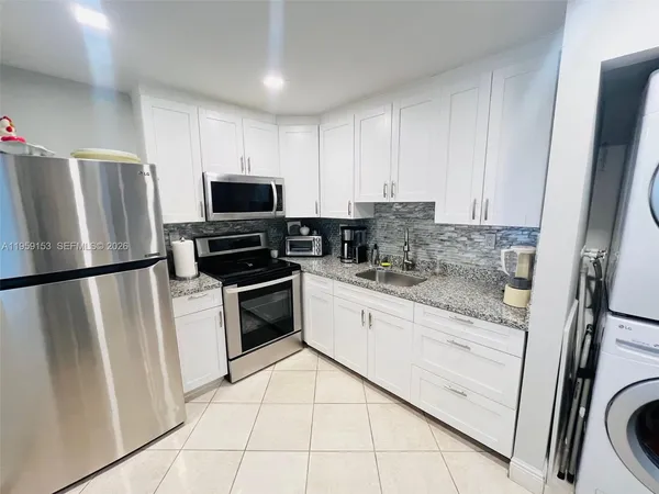 a kitchen with granite countertop a refrigerator sink and microwave