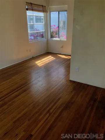 an empty room with wooden floor painted walls and windows