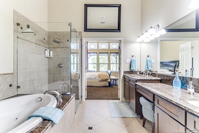 a en suite spacious bathroom with a granite countertop tub sink a mirror a shower and vanity