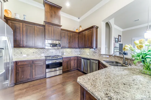 a kitchen with stainless steel appliances granite countertop wooden cabinets a stove a sink and dishwasher