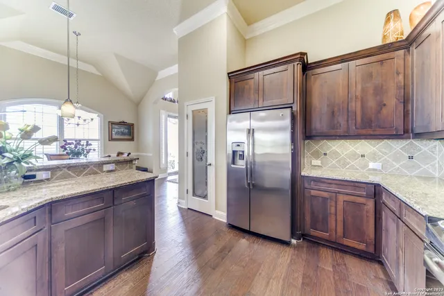 a kitchen with stainless steel appliances granite countertop a refrigerator a sink and wooden cabinets