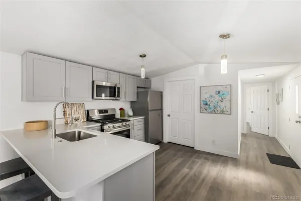 a kitchen with stainless steel appliances granite countertop a sink dishwasher a refrigerator white cabinets with wooden floor
