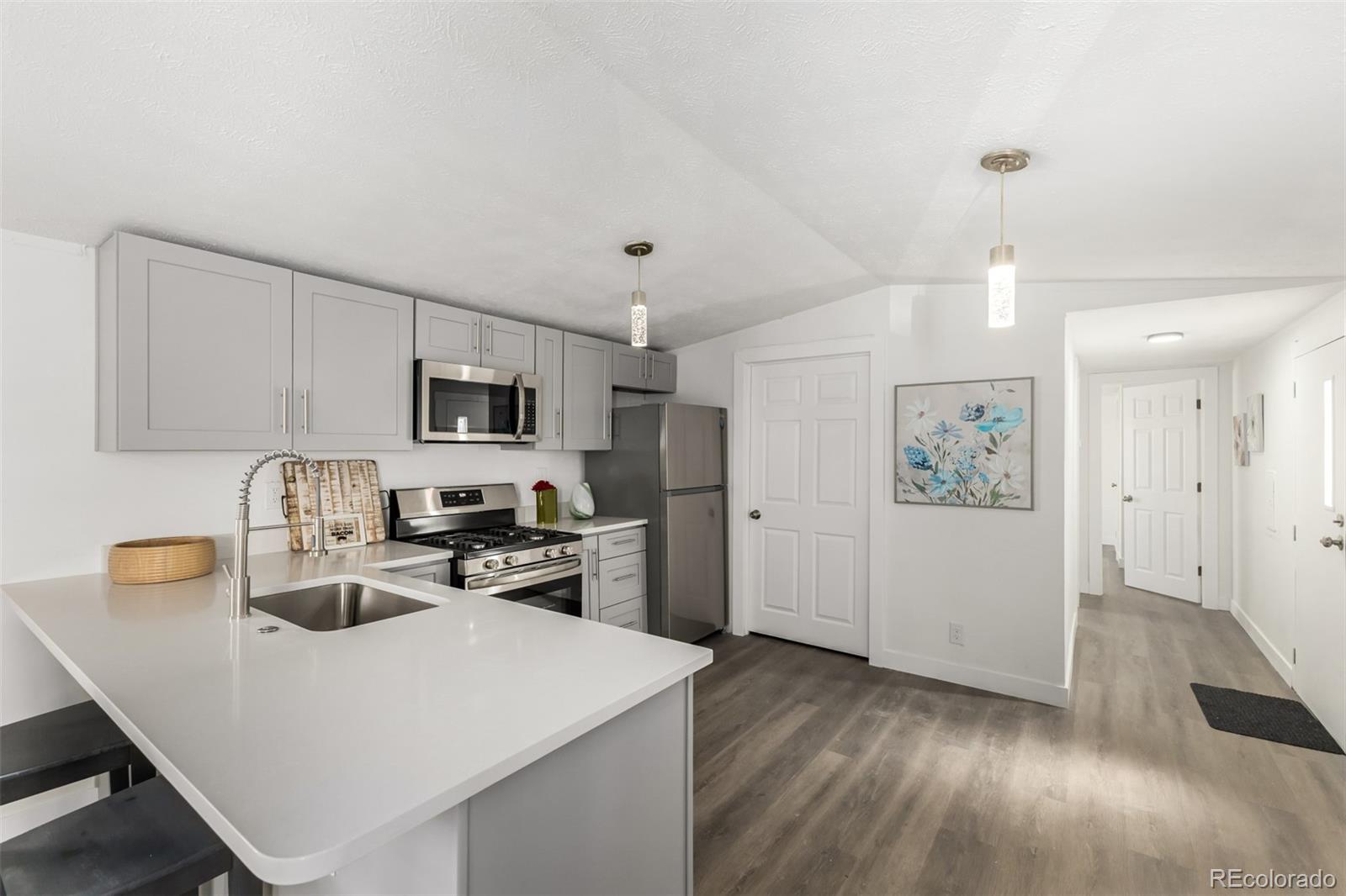 103 North Josephine Avenue Milliken, CO 80543 - Photo 6 of 14 a kitchen with stainless steel appliances granite countertop a sink dishwasher a refrigerator white cabinets with wooden floor