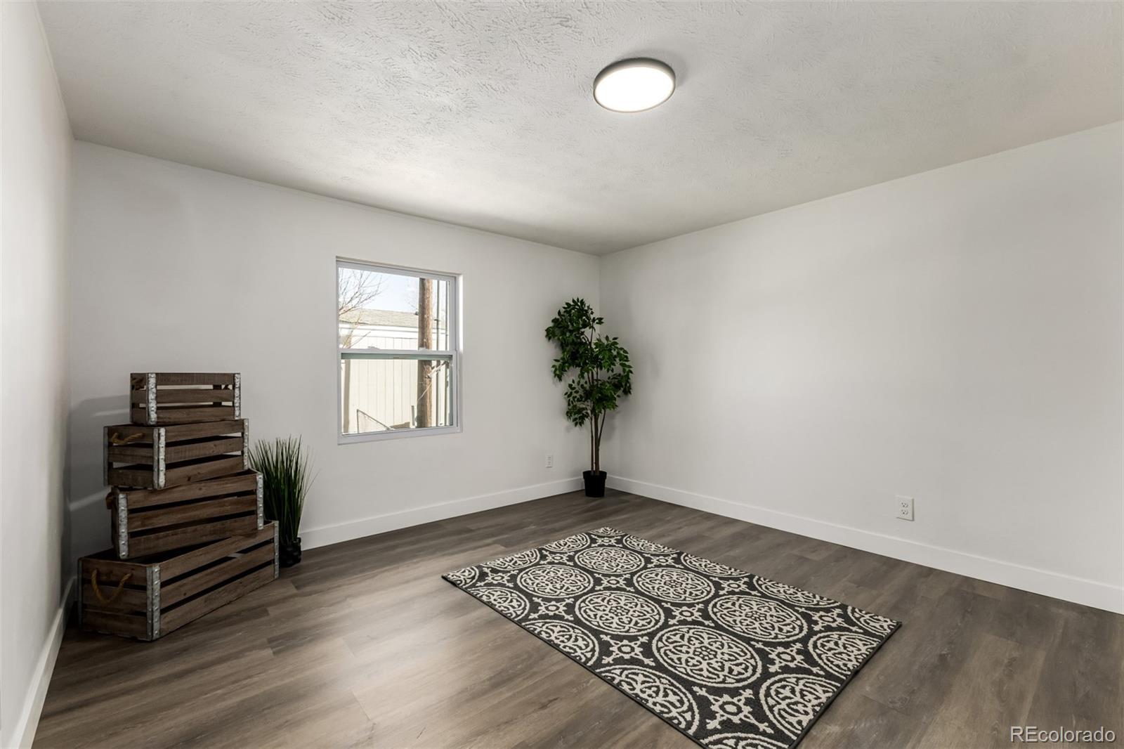 103 North Josephine Avenue Milliken, CO 80543 - Photo 10 of 14 an empty room with wooden floor and windows