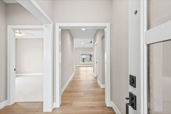 a view of a hallway with wooden floor and a bathroom