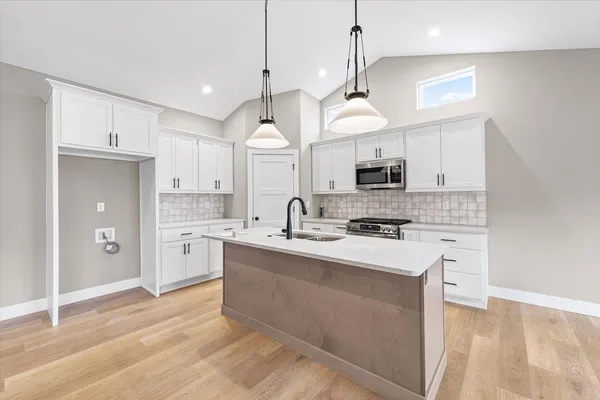 a kitchen with stainless steel appliances granite countertop a sink a stove a refrigerator and island with wooden floor