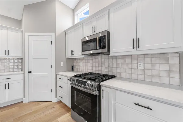 a kitchen with stainless steel appliances white cabinets and stove