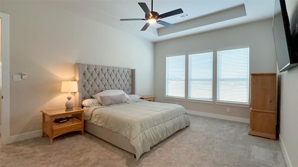 12116 Magma Court Krum, TX 76249 - Photo 13 of 30 a bedroom with a bed and a refrigerator