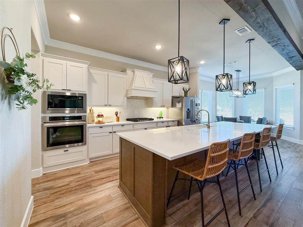 12116 Magma Court Krum, TX 76249 - Photo 8 of 30 a kitchen with stainless steel appliances kitchen island granite countertop a stove a sink dishwasher and a refrigerator with wooden floor
