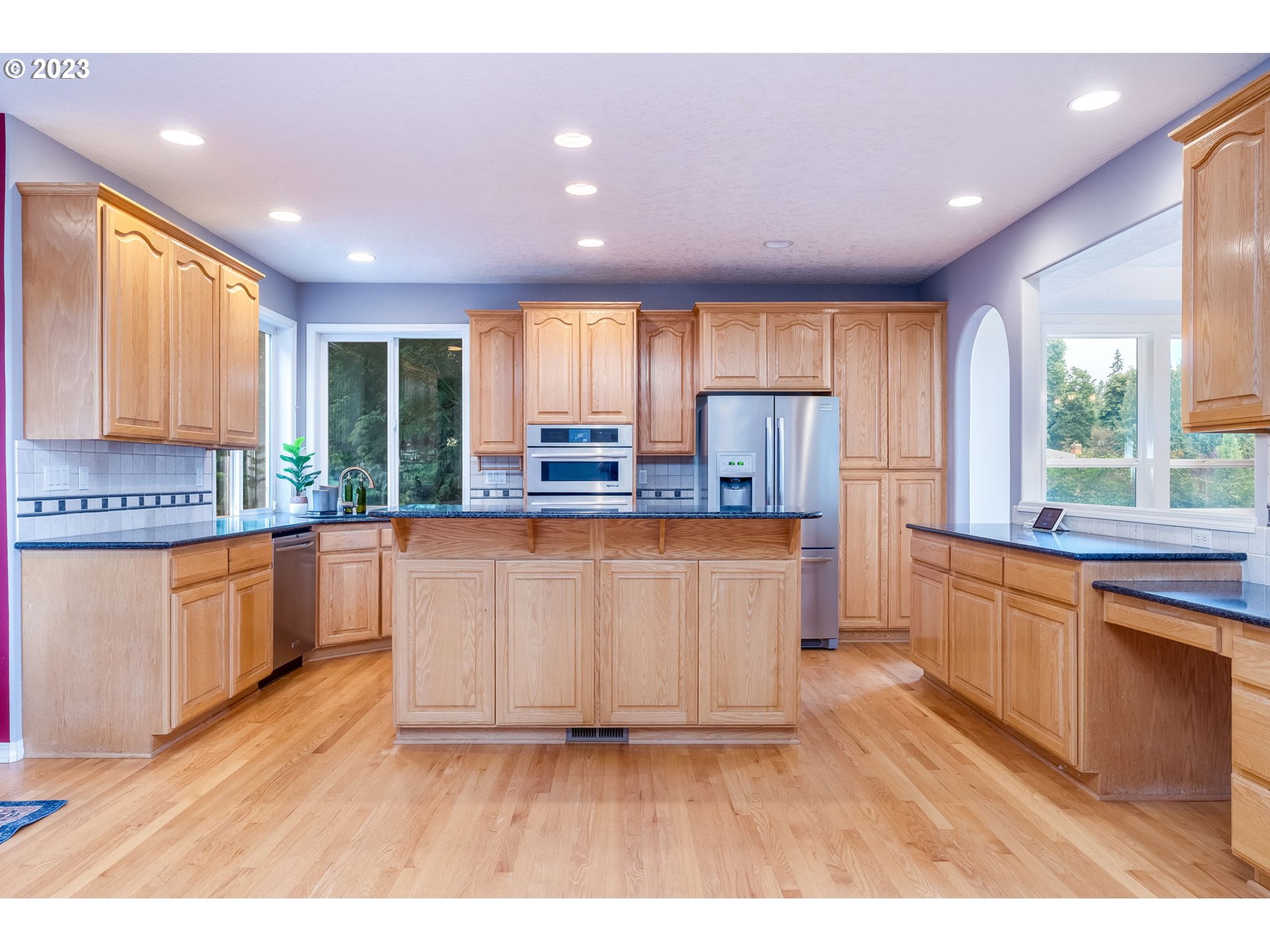 2842 Southeast Morlan Place Gresham, OR 97080 - Photo 10 of 46 a large kitchen with kitchen island granite countertop a stove a sink a refrigerator and white cabinets with wooden floor