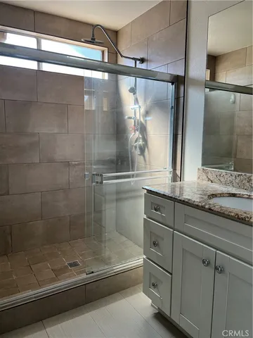 a bathroom with a granite countertop sink a mirror and shower