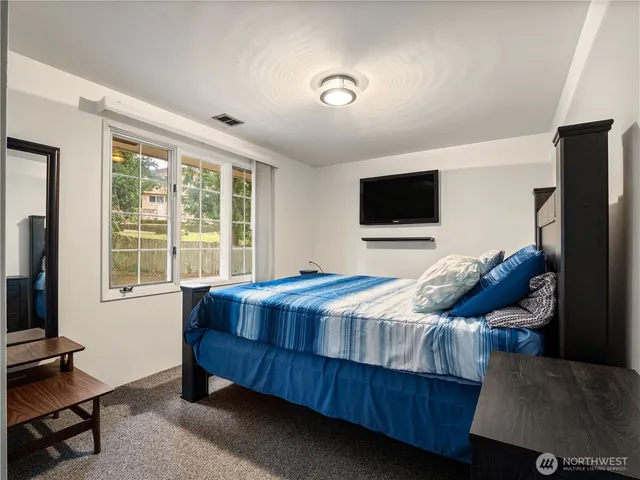 a bedroom with a bed and a flat tv screen on a dresser