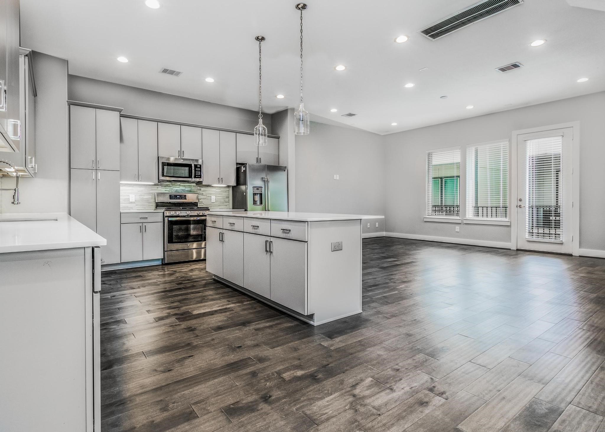8409 Hempstead Road, Unit F Houston, TX 77008 - Photo 12 of 23 a kitchen with stainless steel appliances kitchen island granite countertop a stove a sink a refrigerator and a microwave