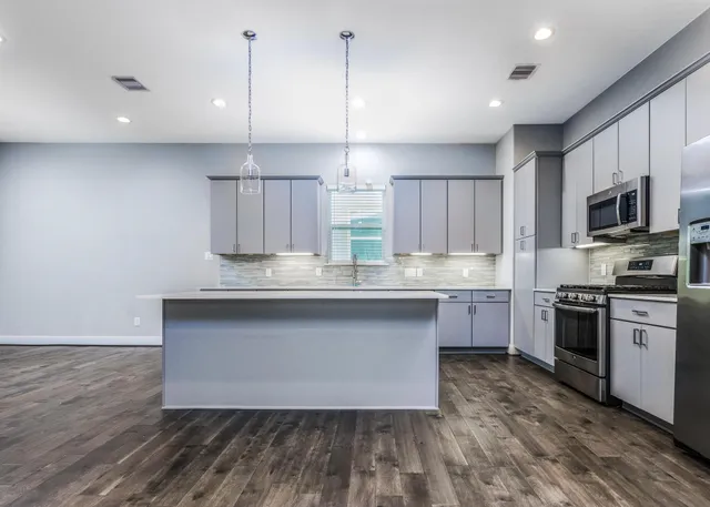 a kitchen with stainless steel appliances granite countertop a sink a stove a microwave a center island and cabinets