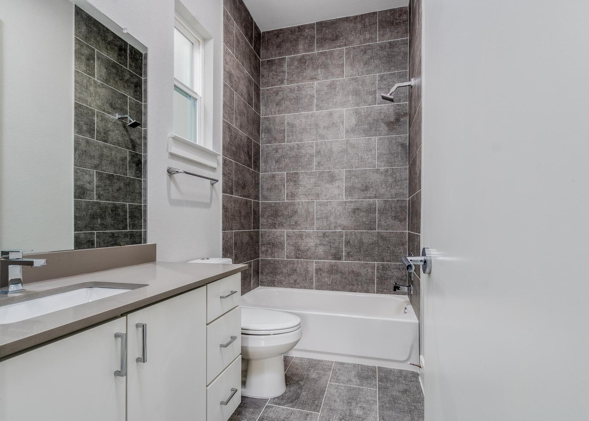 8409 Hempstead Road, Unit F Houston, TX 77008 - Photo 22 of 23 a bathroom with a granite countertop bathtub shower sink vanity and toilet