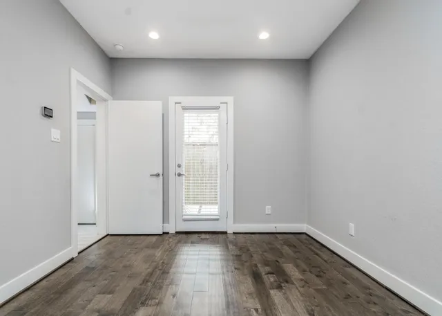 an empty room with wooden floor and window