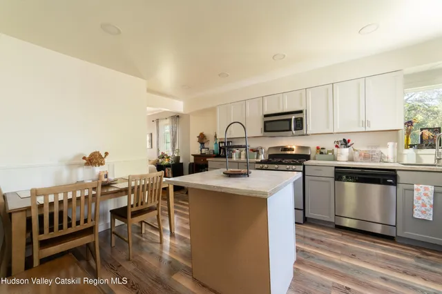 a kitchen with stainless steel appliances granite countertop a stove top oven a sink dishwasher a dining table and chairs with wooden floor