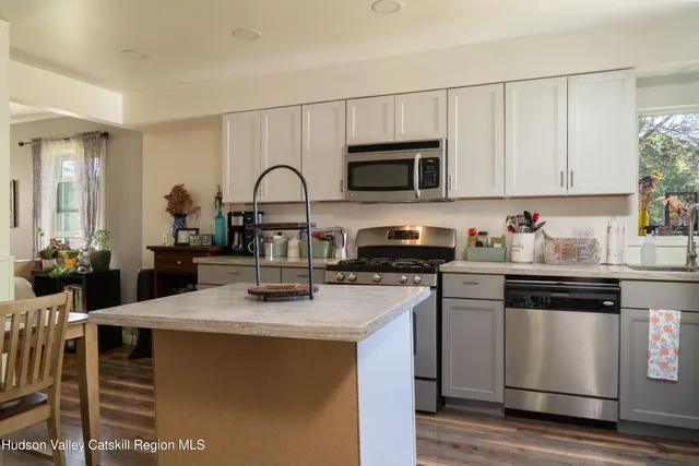 a kitchen with stainless steel appliances granite countertop a stove a sink dishwasher and a microwave with wooden cabinets