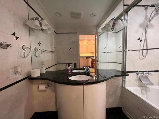 a bathroom with a granite countertop sink a mirror and shower