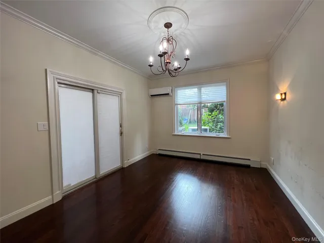 an empty room with wooden floor chandelier and windows