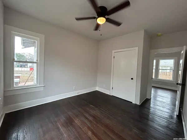 an empty room with wooden floor and windows