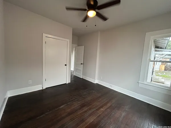 an empty room with wooden floor cabinet and windows