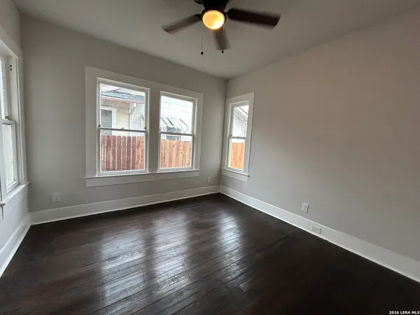 a view of an empty room with wooden floor and a window