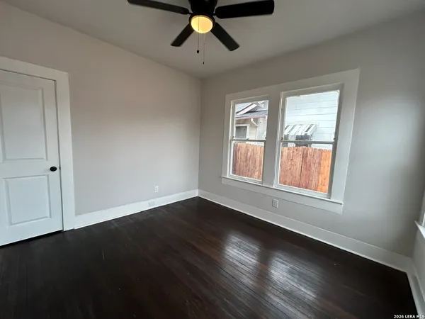 a view of an empty room with wooden floor and a window