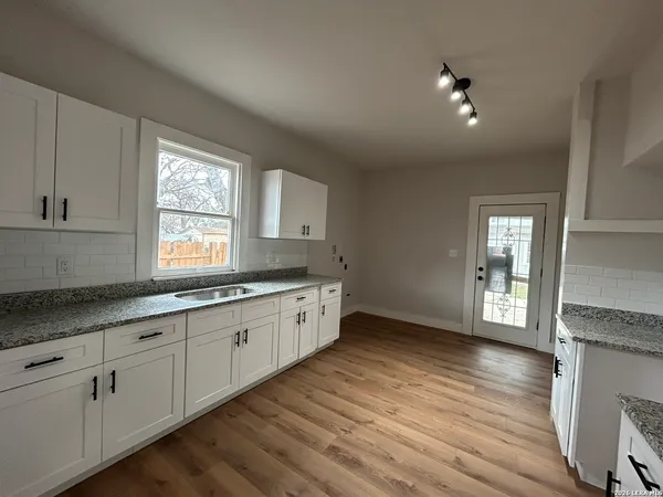 a kitchen with granite countertop white cabinets and wooden floor