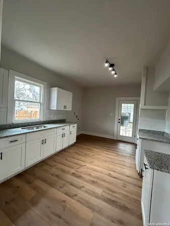 a kitchen with stainless steel appliances granite countertop a sink cabinets and wooden floor
