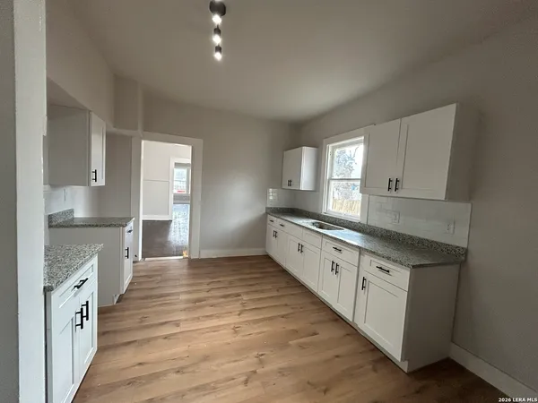 a large kitchen with cabinets wooden floor and a sink
