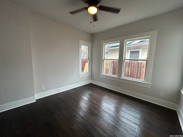 a view of an empty room with wooden floor and a window