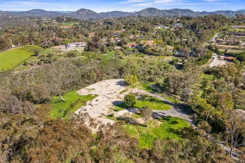 a view of a lush green field with mountains in the background