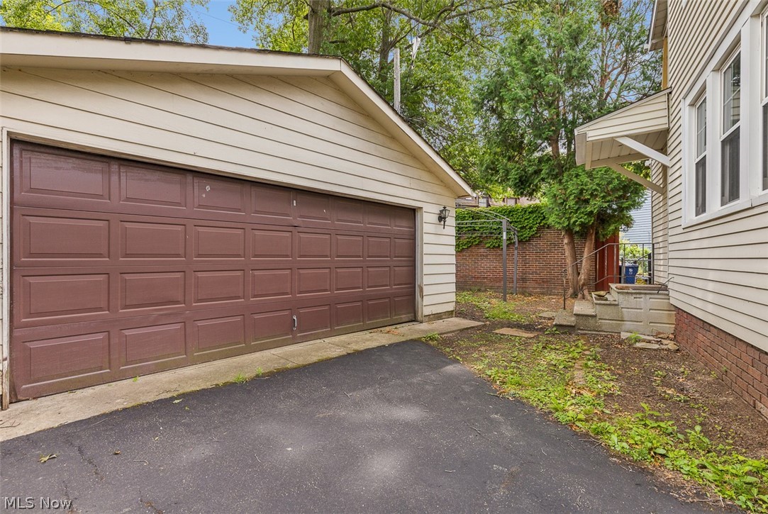 2972 Yorkshire Road Cleveland Heights, OH 44118 - Photo 40 of 44 Detached garage with a brown panel door, light-colored siding, and a paved driveway