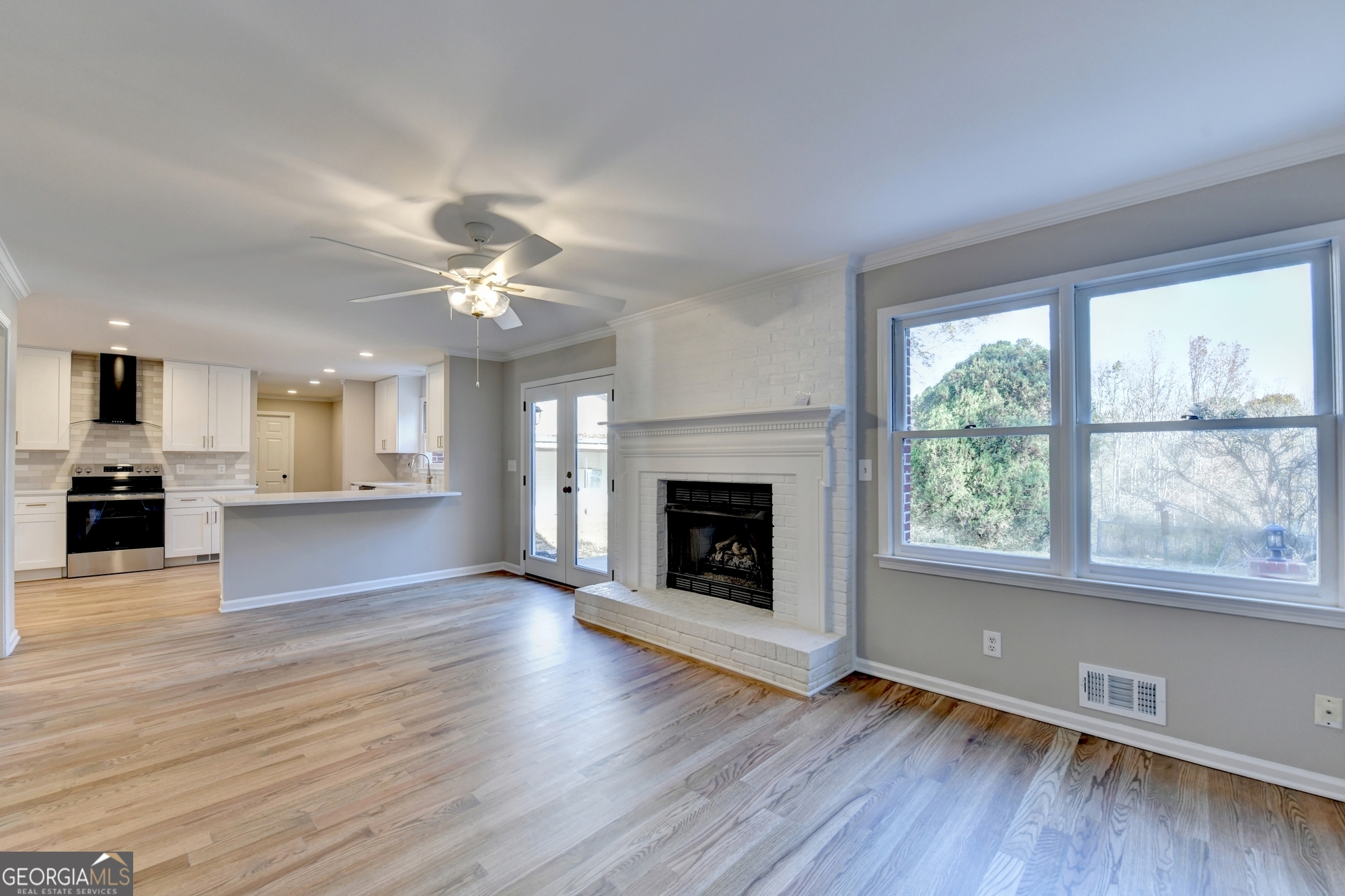 590 Manning Gin Road Monroe, GA 30656 - Photo 27 of 76 an empty room with wooden floor a kitchen view and a fireplace