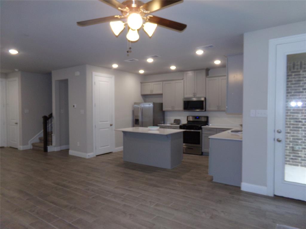Kitchen with a kitchen island, appliances with stainless steel finishes, light countertops, gray cabinetry, and recessed lighting