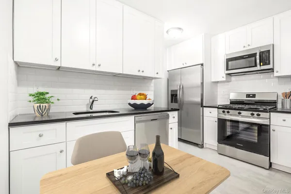 a kitchen with stainless steel appliances kitchen island granite countertop a refrigerator a stove a sink and white cabinets