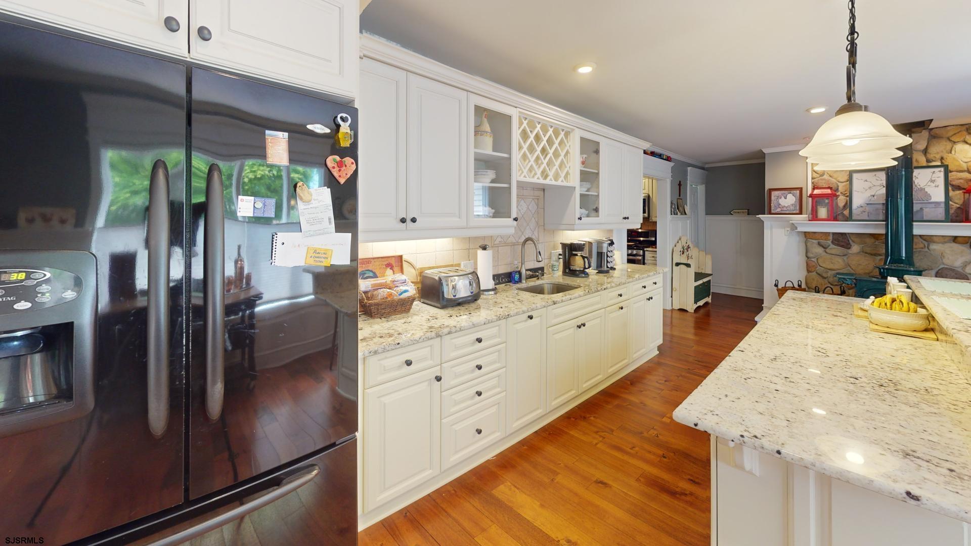 228 Marlin Road Absecon, NJ 08201 - Photo 10 of 24 a kitchen with stainless steel appliances kitchen island granite countertop a refrigerator a oven a stove and a dining table with wooden floor
