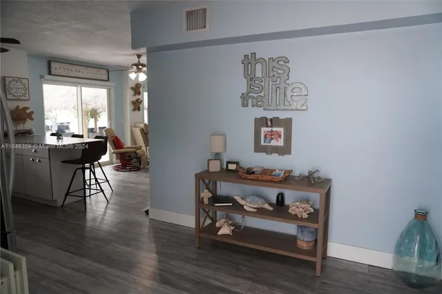 a living room with furniture floor to ceiling window hardwood floor and a flat screen tv