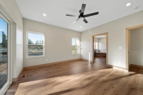 a view of an empty room with window and chandelier fan