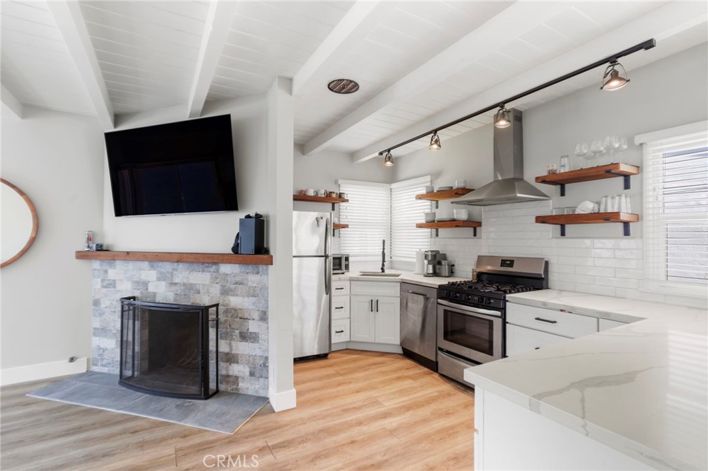 27 66th Place Long Beach, CA 90803 - Photo 13 of 56 a kitchen with stainless steel appliances granite countertop a stove top oven a sink dishwasher and a fireplace with wooden floor