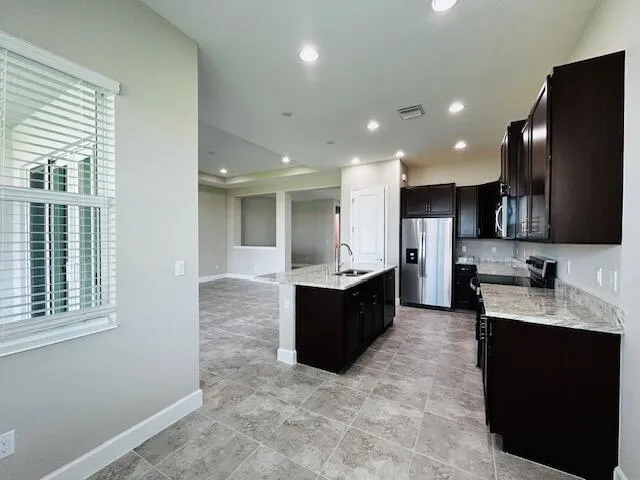 a large kitchen with stainless steel appliances kitchen island granite countertop a large counter top and a sink